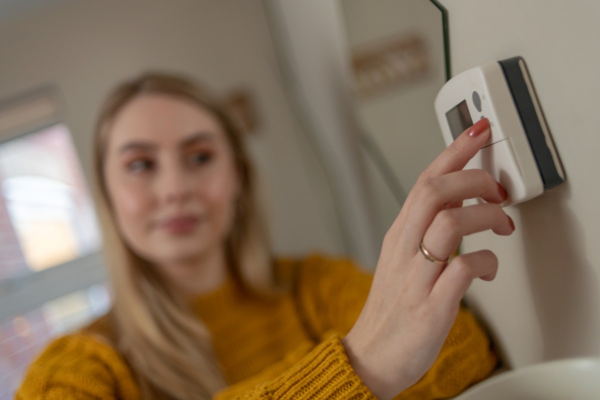 Una donna che imposta la temperatura dal termostato
