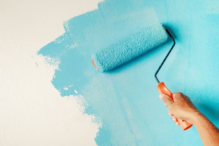 Un uomo che pittura il muro di celeste un muro