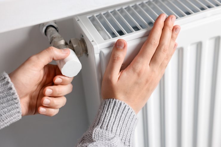Un uomo che accende i termosifoni e ne sente la temperatura con la mano