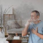 Un uomo che tossisce per via dello smog nella sua casa