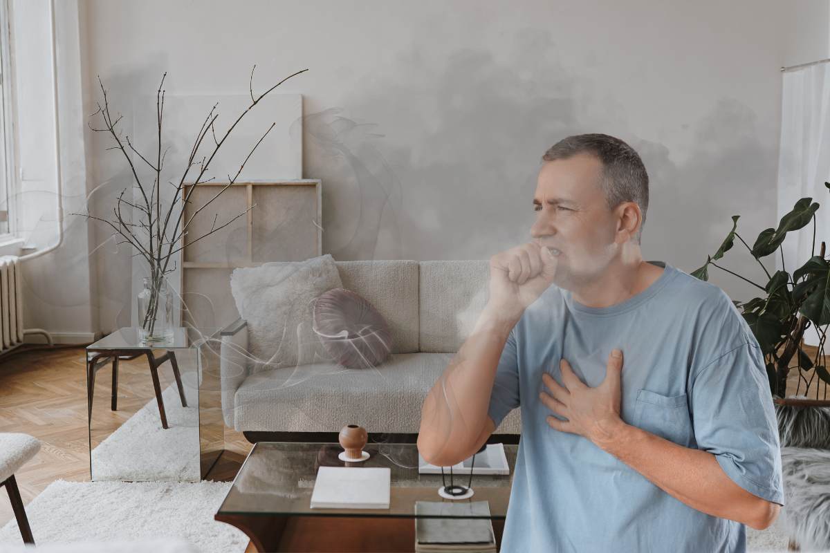 Un uomo che tossisce per via dello smog nella sua casa