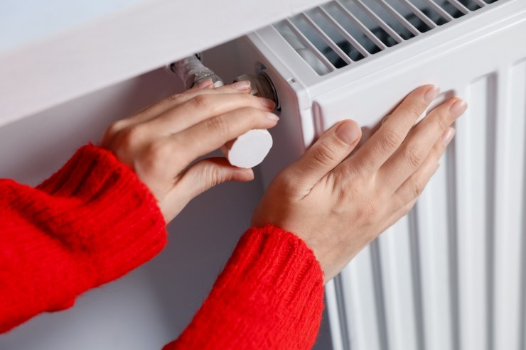 Una persona che sente la temperatura dei termosifoni con le mani