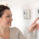 Una donna che spegne i termosifoni dal termostato