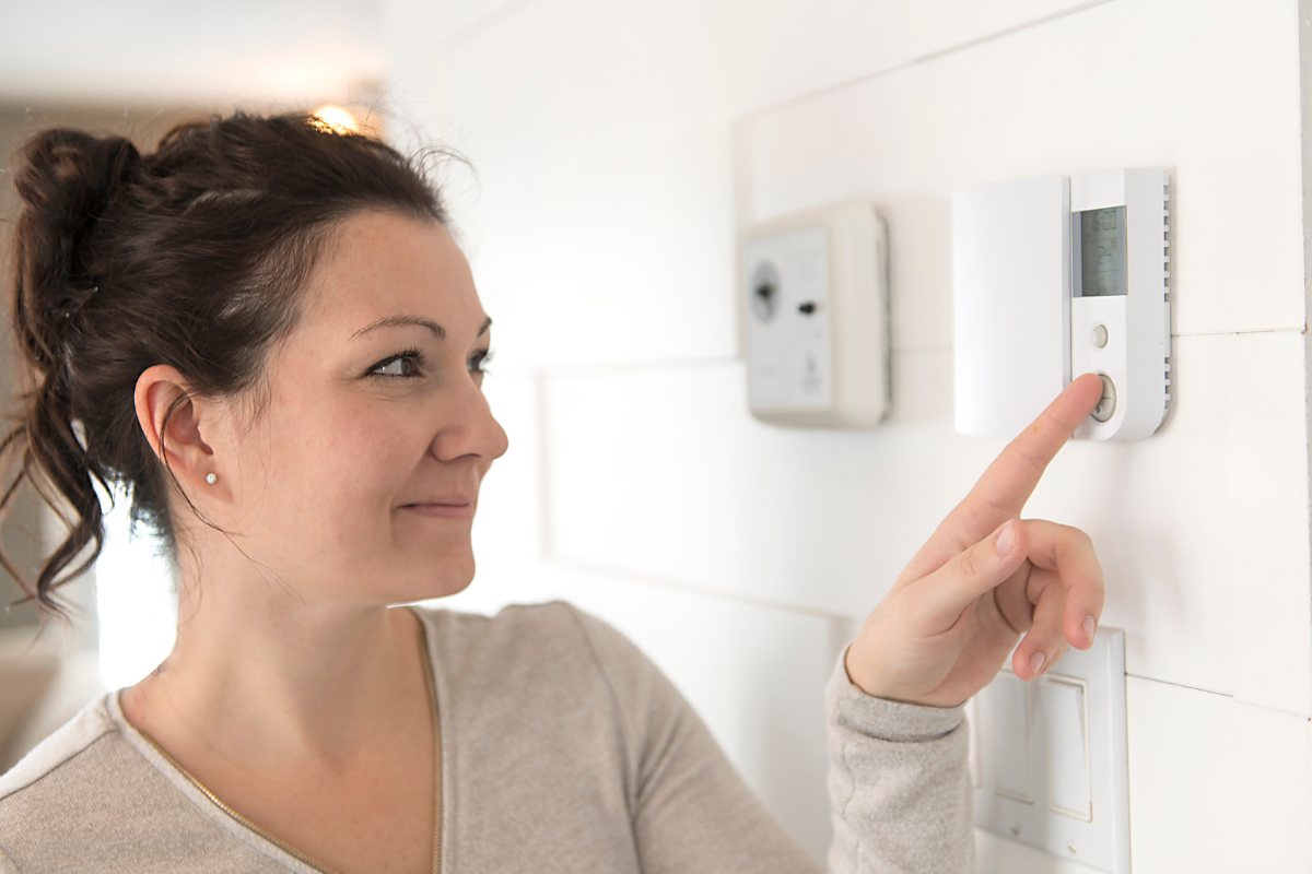 Una donna che spegne i termosifoni dal termostato