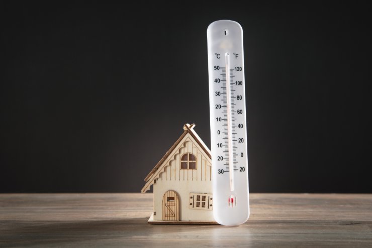 Una miniatura di una casa con un termometro appoggiato sopra