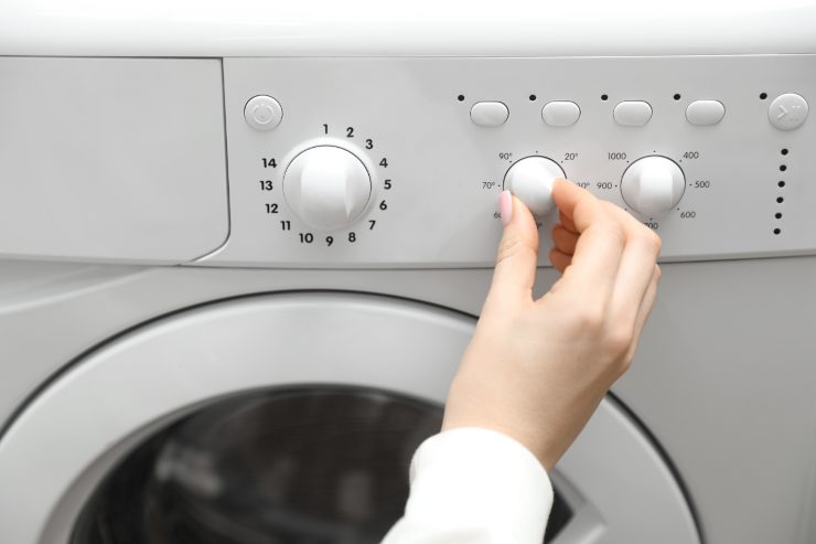 Una persona che imposta la temperatura per la lavatrice