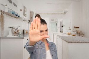 donna in primo piano che dice stop ad una cucina completamente bianca