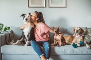 donna sul divano con i suoi cani mentre ne bacia uno