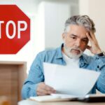 uomo preoccupato che legge bolletta e scritta stop