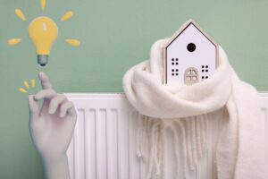 termosifone con casa con sciarpa e mano con lampadina