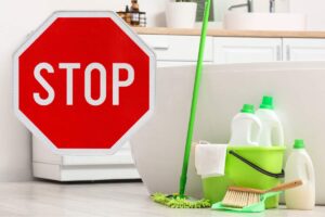 bagno con prodotti per la pulizia di colore verde e cartello con scritto stop