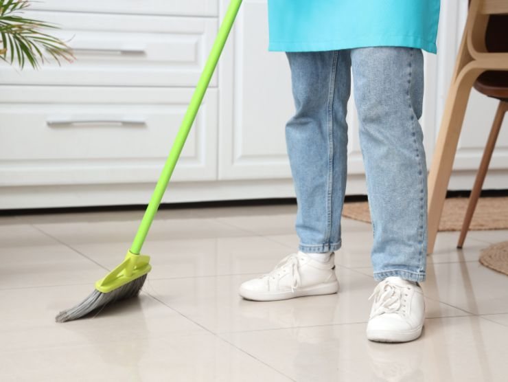persona che passa scopa sul pavimento