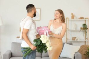 uomo che consegna regalo e fiori ad una donna