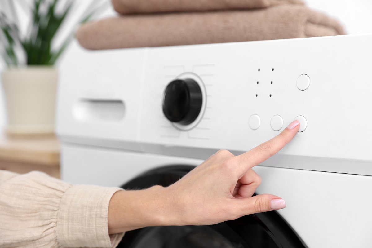 mano che preme su lavatrice 