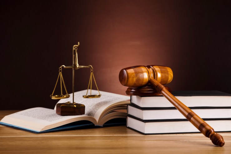 Un tavolo con sopra libri di legge, una bilancia ed un martello da giudice