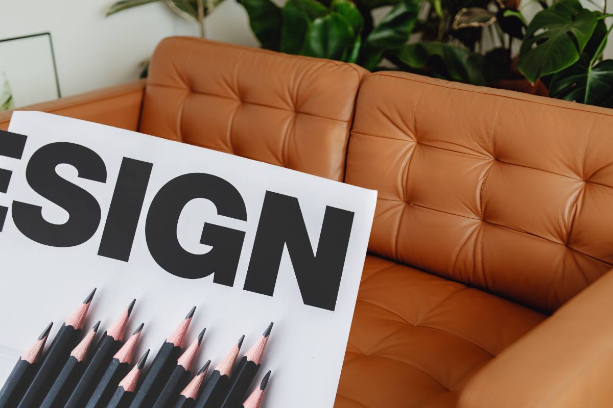 divano in pelle marrone con scritta design su giornale e matite nere