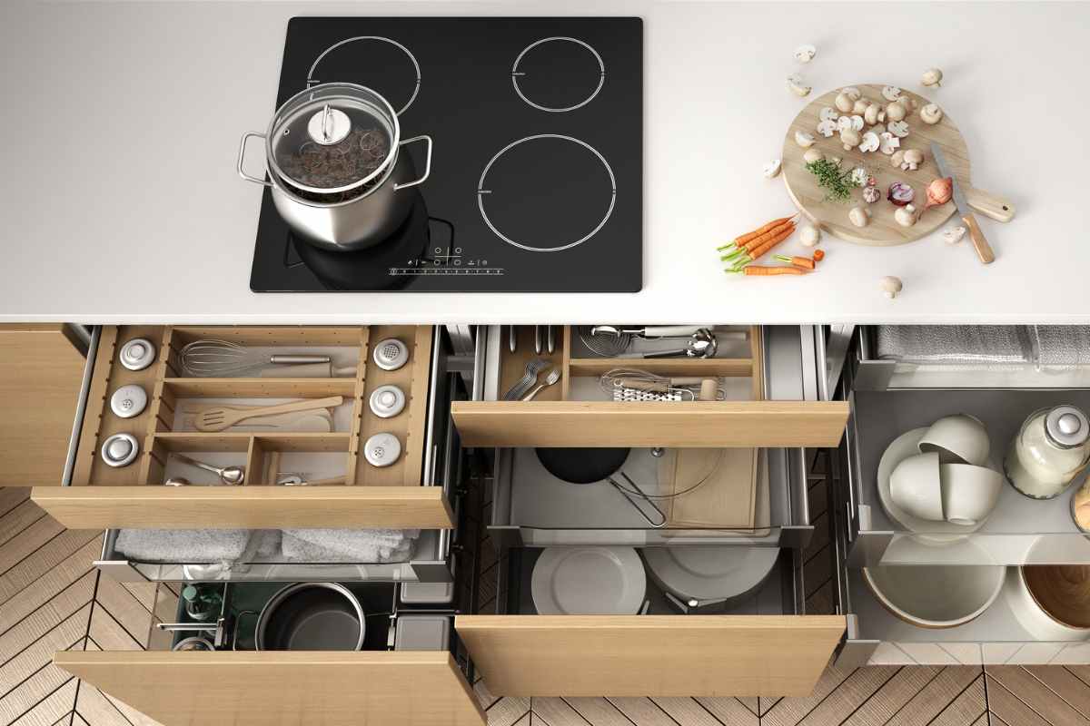 cucina con piano ad induzione e cassetti sistemati con oggetti vari 