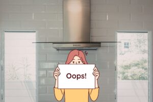 cappa in cucina e disegno di una donna con cartello su cui c'è scritto oops