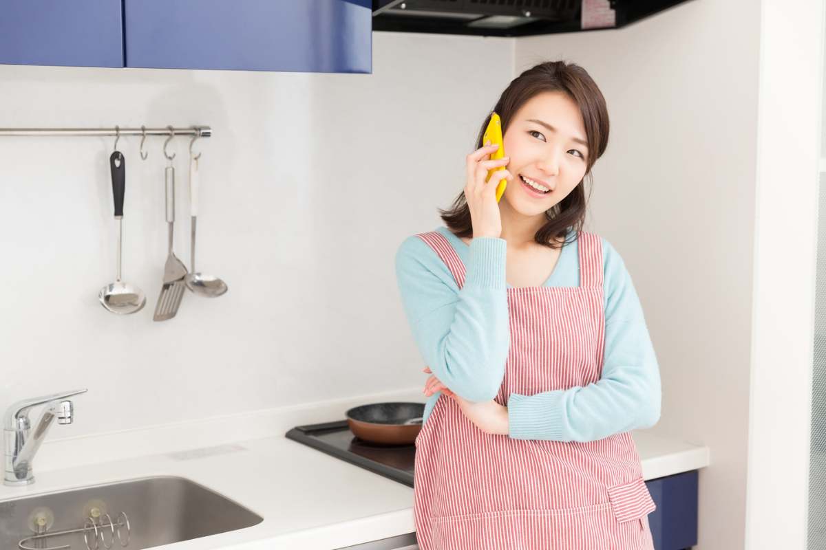 donna con grembiule da cucina che è al telefono