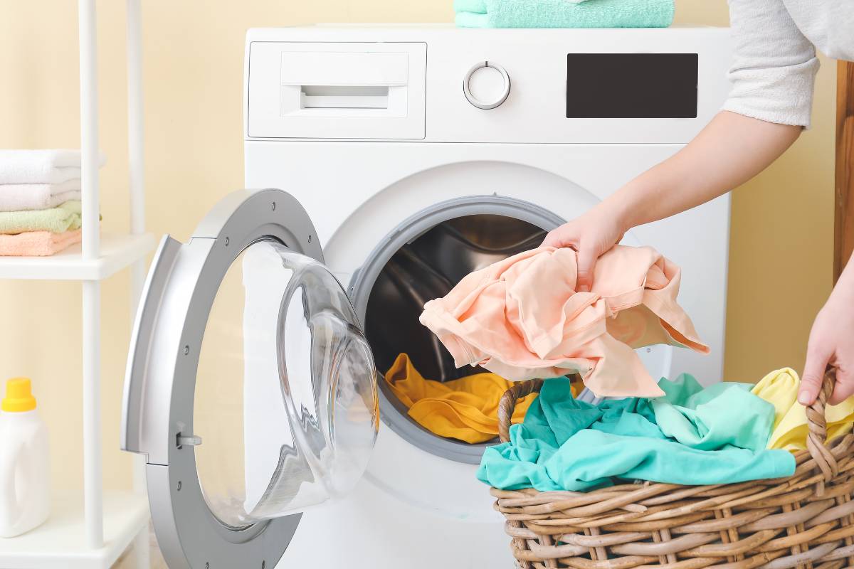 Una persona che mette il bucato in lavatrice