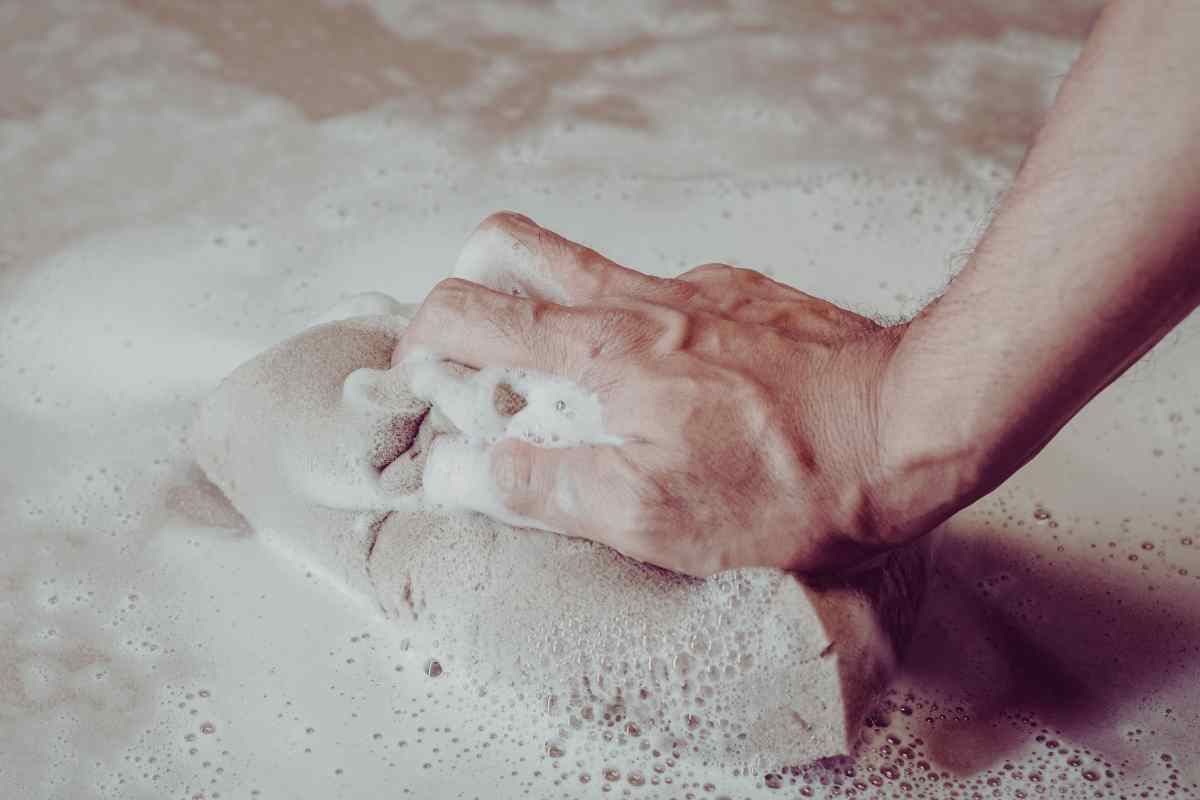 mano che pulisce il marmo con schiuma
