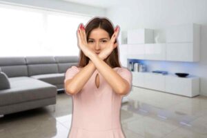 donna che fa no con le mani di fronte ad un salotto con mobili bianchi e lucidi