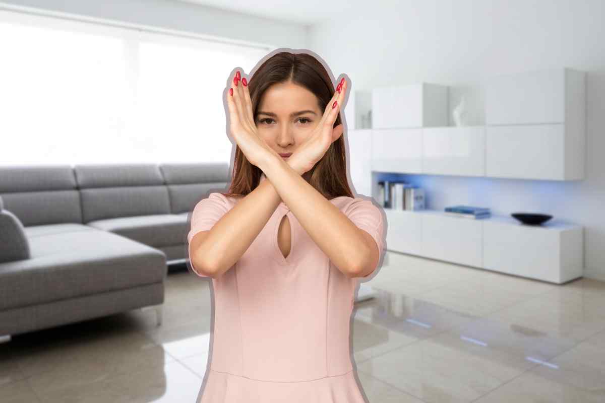 donna che fa no con le mani di fronte ad un salotto con mobili bianchi e lucidi