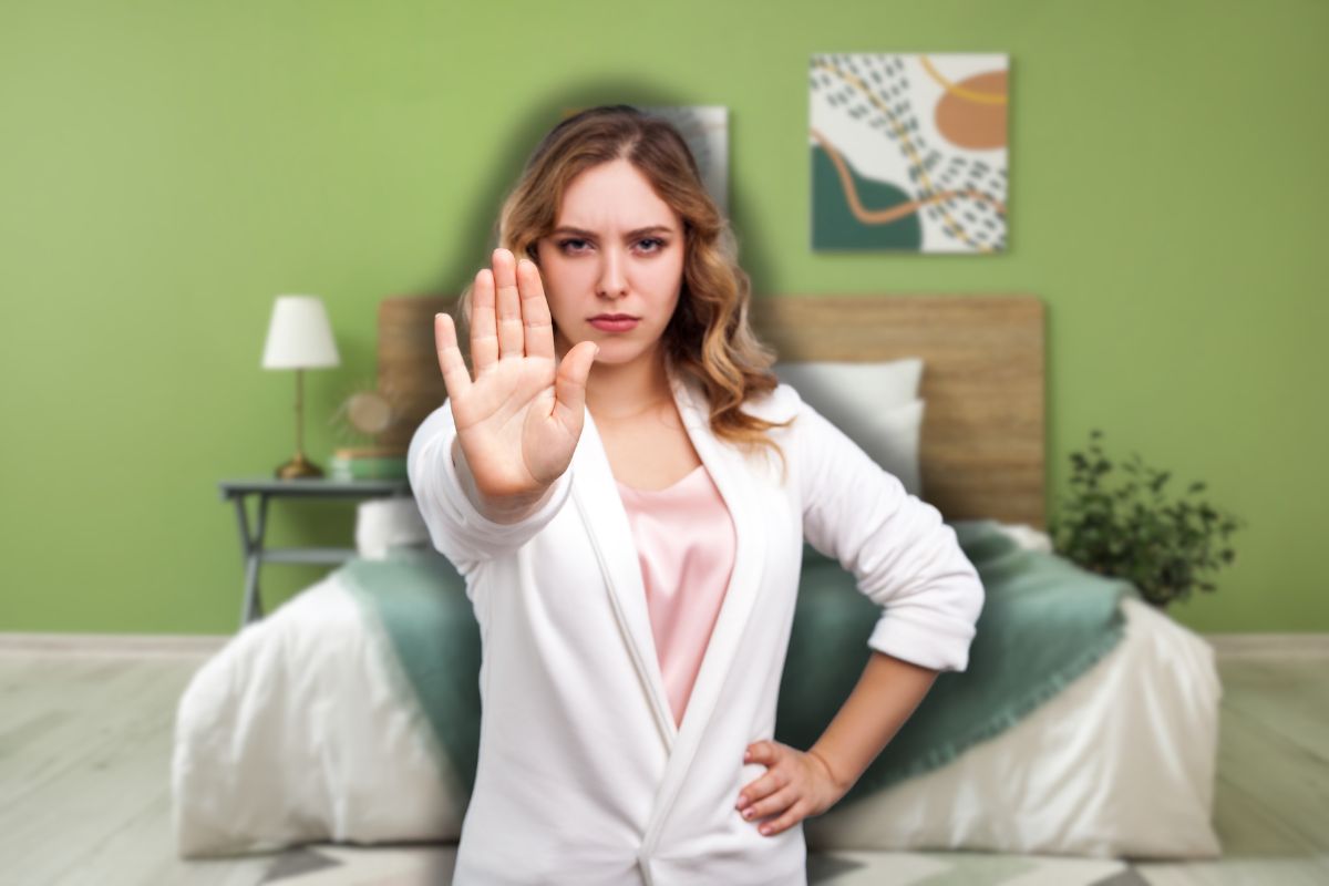 letto matrimoniale e donna che fa stop con le mani