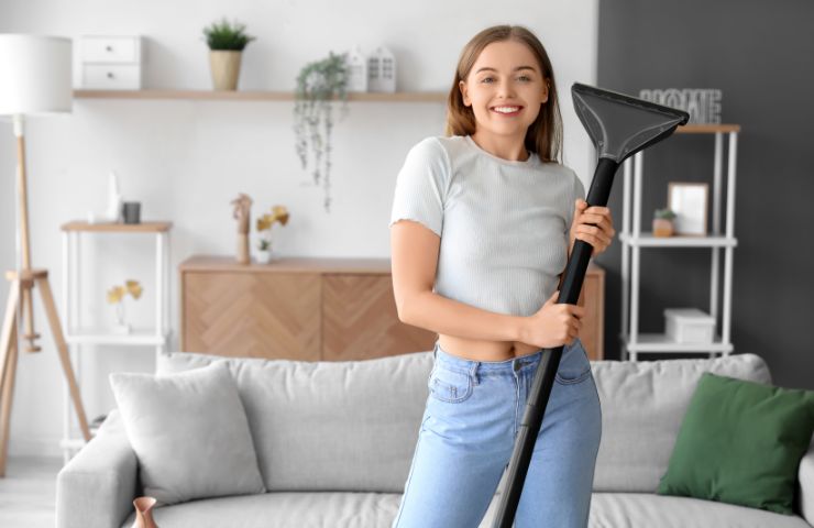 donna sorridente con aspirapolvere in mano