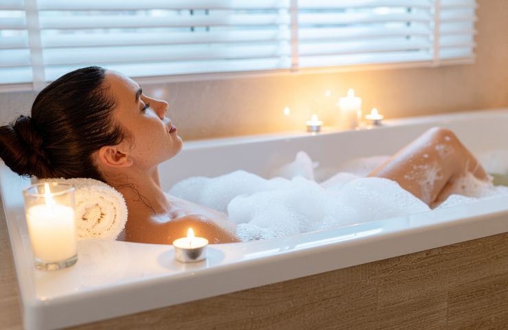 donna nella vasca da bagno con candele attorno