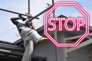 muratore su ponteggio e scritta stop in rosso