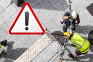 tecnici che montano ponteggi con il caschetto e simbolo attenzione