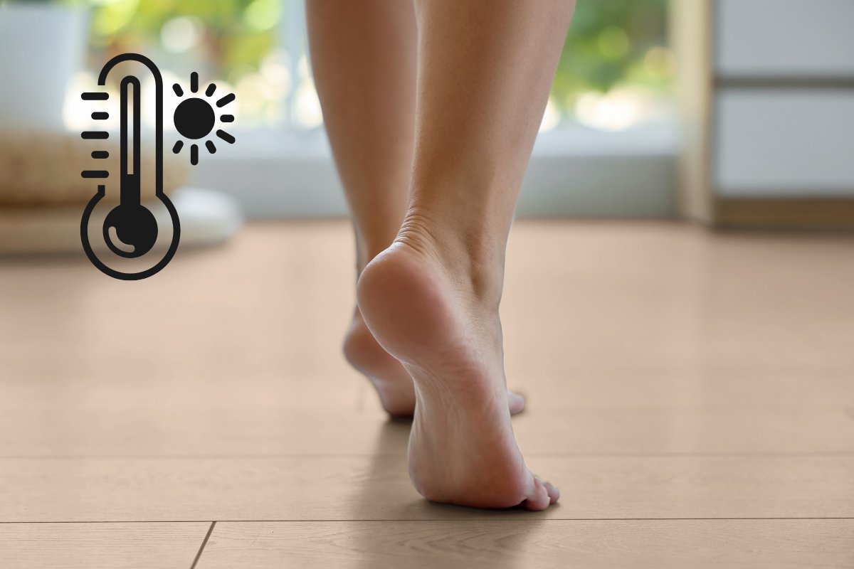 Una donna che cammina scalza sul pavimento di casa e in alto a sinistra il simbolo di un termometro