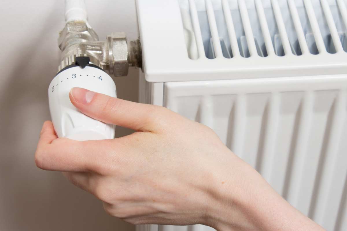 mano che gira manopola sul termosifone