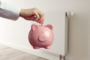 termosifone e mano con salvadanaio a forma di maialino rosa