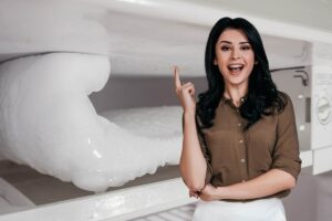 Donna con idea e alle spalle congelatore con ghiaccio