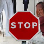 donna che stende i panni e segnale con scritta stop
