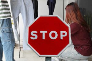 donna che stende i panni e segnale con scritta stop