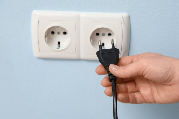 Una mano che stacca una spina dalla presa