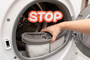 Una persona che adopera l'asciugatrice ed una scritta "stop" sopra