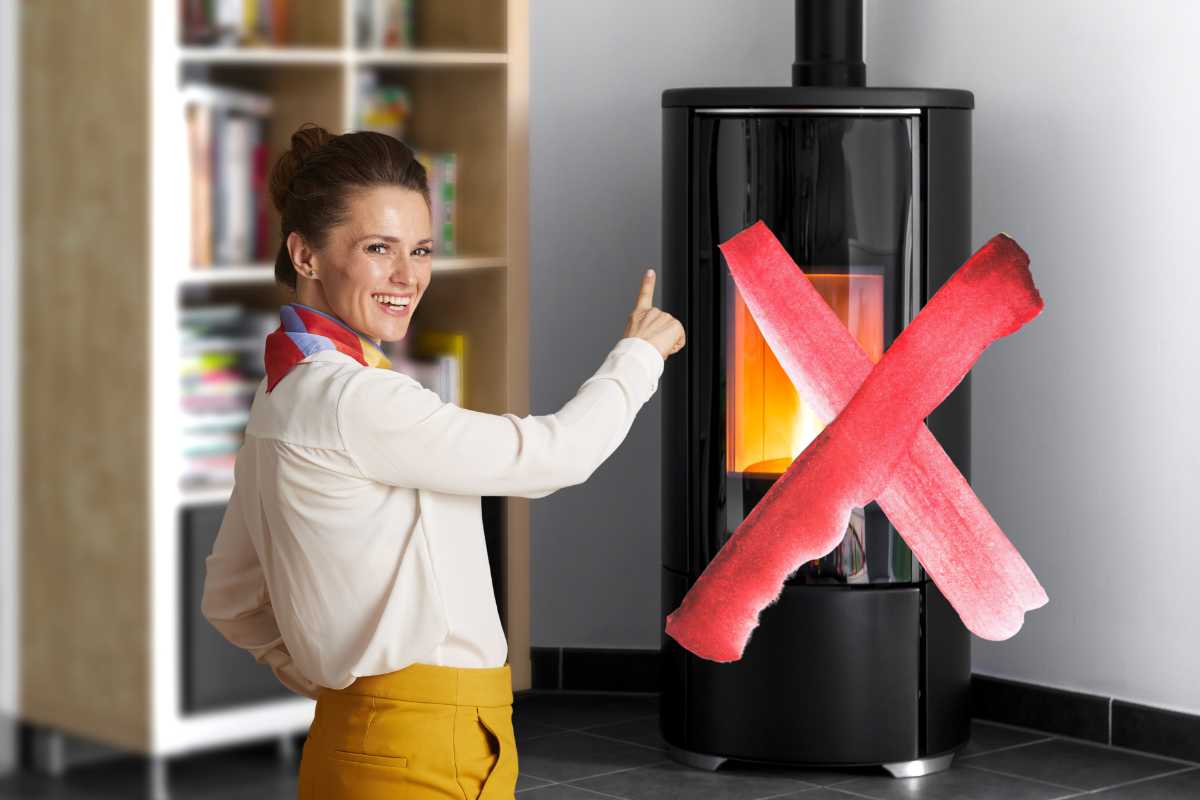 donna che indica una stufa a pellet in casa che ha una x rossa sopra