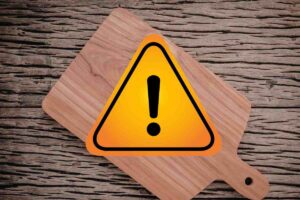 tagliere su tavolo di legno e simbolo attenzione giallo e nero