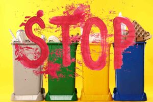 cassonetti con dentro spazzatura e scritta stop in rosso
