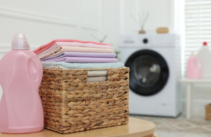 lavatrice e cesta con il bucato e detersivo