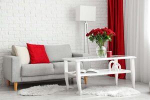 Una salone con un tavolo con sopra un vaso in vetro con dentro i fiori