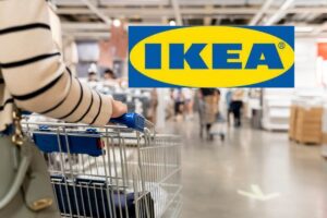 Una persona che spinge il carrello nel negozio ed in alto a sinistra l'insegna di Ikea