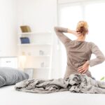 Una donna che si alza dal letto con il man di schiena