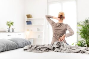 Una donna che si alza dal letto con il man di schiena