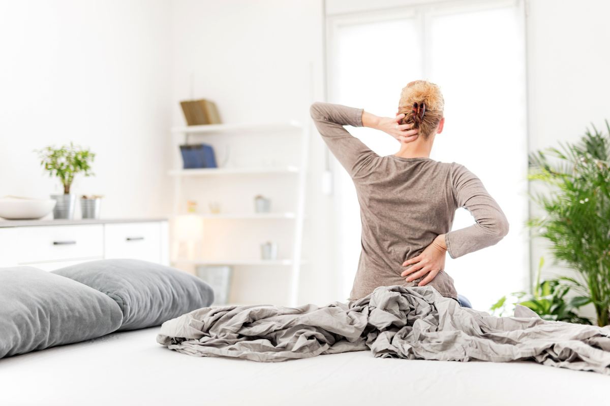 Una donna che si alza dal letto con il man di schiena