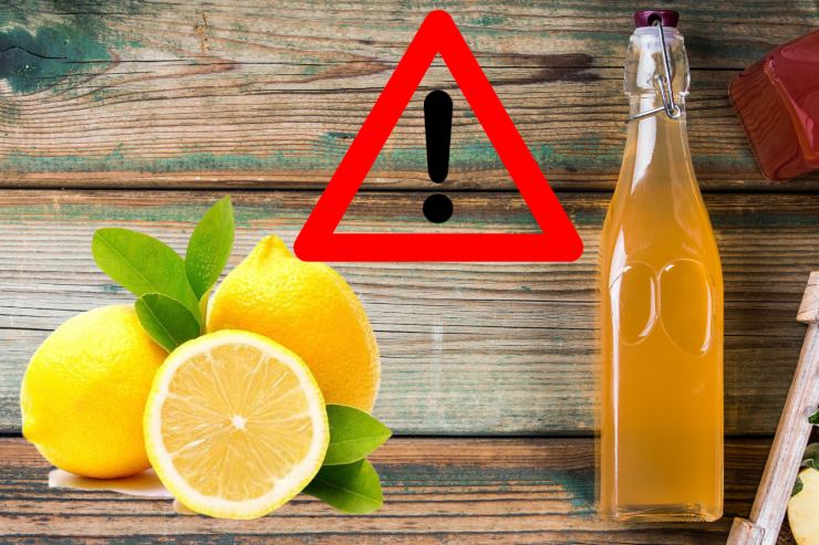 Un tavolo con sopra limoni ed una bottiglia di aceto ed in alto in primo piano un segnale di pericolo